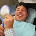 Jean-Claude Soloman checks out his new teeth for the first time after losing his front teeth from an assault in 2010. Melanie Maxwell I AnnArbor.com